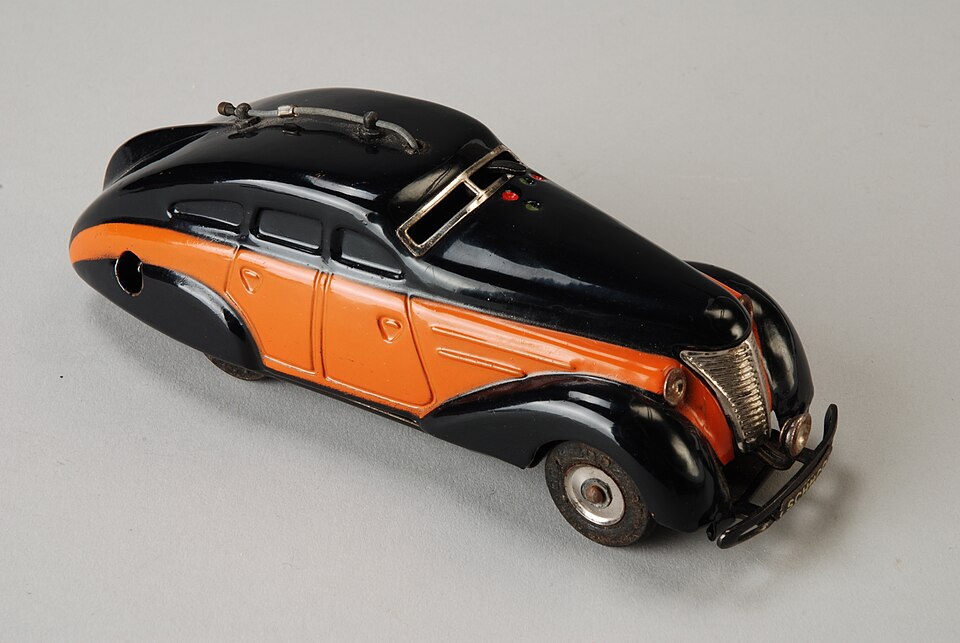 Zwarte Schuco speelgoedauto met oranje baan over zijden, model “Radio 5000”, in originele doos met handleiding, met twee opwindmechanismen, één voor rijden, één voor muziek (speeldoosje), objectnr 66029-A-D(1), a model car by Schuco