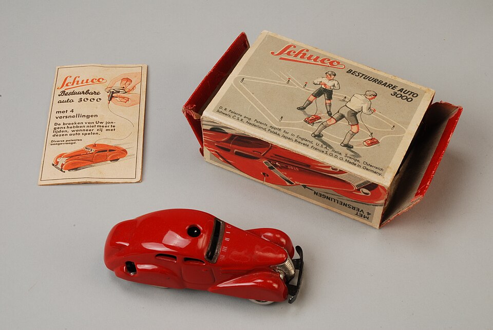 Rode Schuco bestuurbare auto 3000, opwindauto met stuursysteem met draden, opwindsleutel, stuur, twaalf kegels, twee vlaggen (rood en geel) en bal in rek, met originele doos en handleiding, objectnr 66027-A-G(2), a model car by Schuco