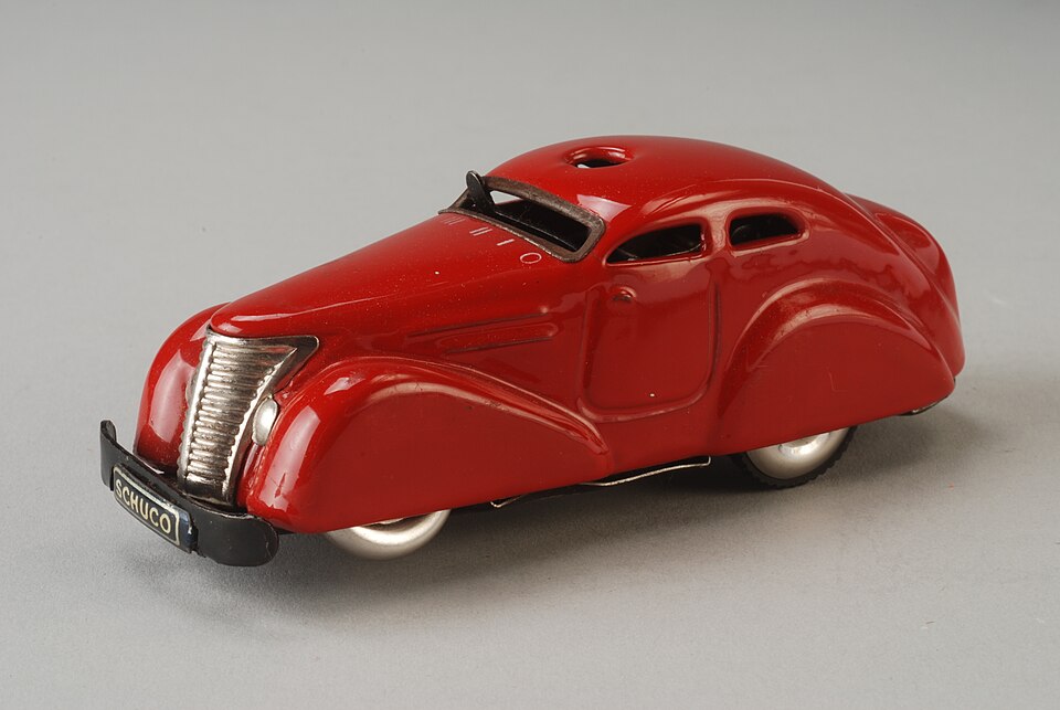 Rode Schuco bestuurbare auto 3000, opwindauto met stuursysteem met draden, opwindsleutel, stuur, twaalf kegels, twee vlaggen (rood en geel) en bal in rek, met originele doos en handleiding, objectnr 66027-A-G(1), a model car by Schuco